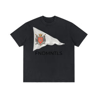 Dark Gray Standard Bearer Vintage Wash T-Shirt with a waving flag and medieval crest with the brand name, FNDMNTLS, below the flag