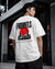A man wearing a white t-shirt with a large black and red graphic print on the back, standing in a modern concrete industrial setting.