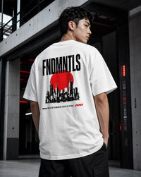 A man wearing a white t-shirt with a large black and red graphic print on the back, standing in a modern concrete industrial setting.