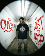 Model wearing One Piece Essential Cotton T-Shirt in black with compass and skull design, styled for urban streetwear in graffiti tunnel.