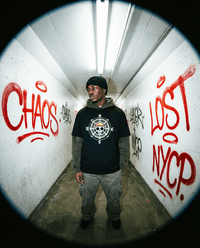 Model wearing One Piece Essential Cotton T-Shirt in black with compass and skull design, styled for urban streetwear in graffiti tunnel.