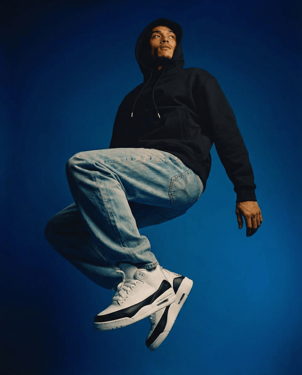 Model wearing Essential Cotton T-Shirt hoodie in black, styled with light denim and sneakers, showcasing casual streetwear appeal.