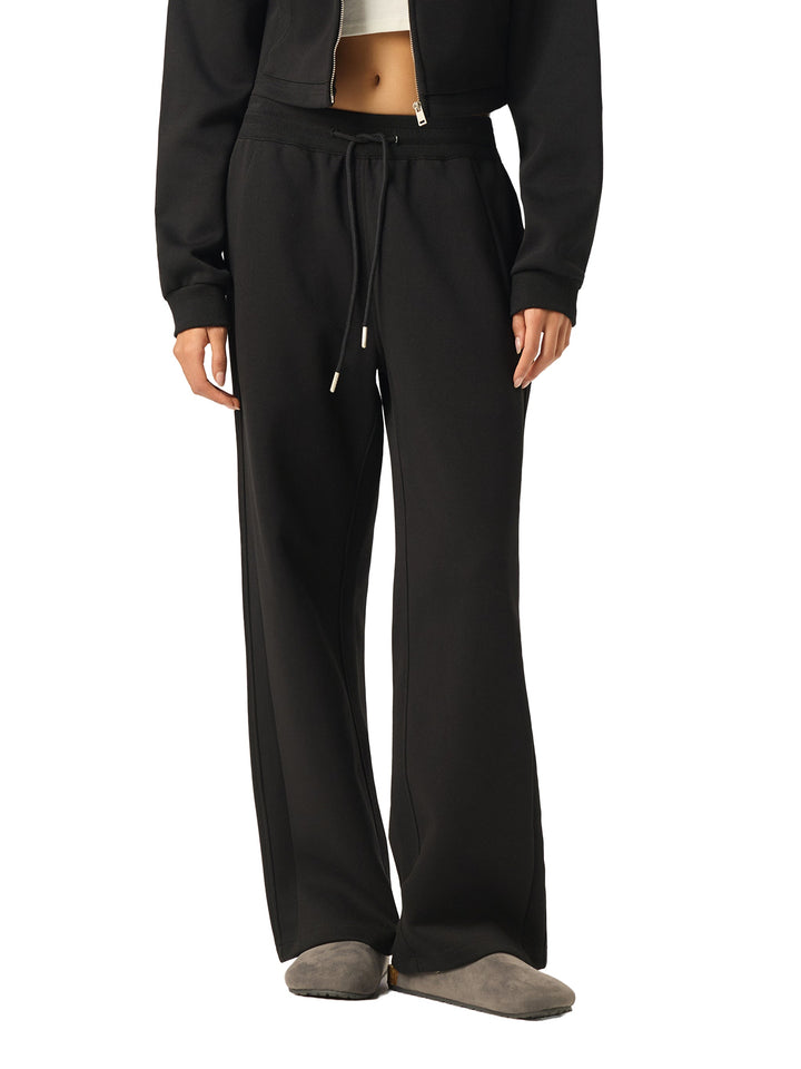 Side view of model in black Essential Drawstring Straight-Leg Sweatpants, showcasing relaxed fit and drawstring waist.