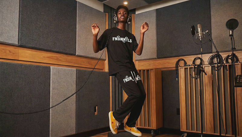 FNDMNTLS Flared Sweatpants in black worn in studio setting, highlighting flared cut and bold branding for stylish casual wear.