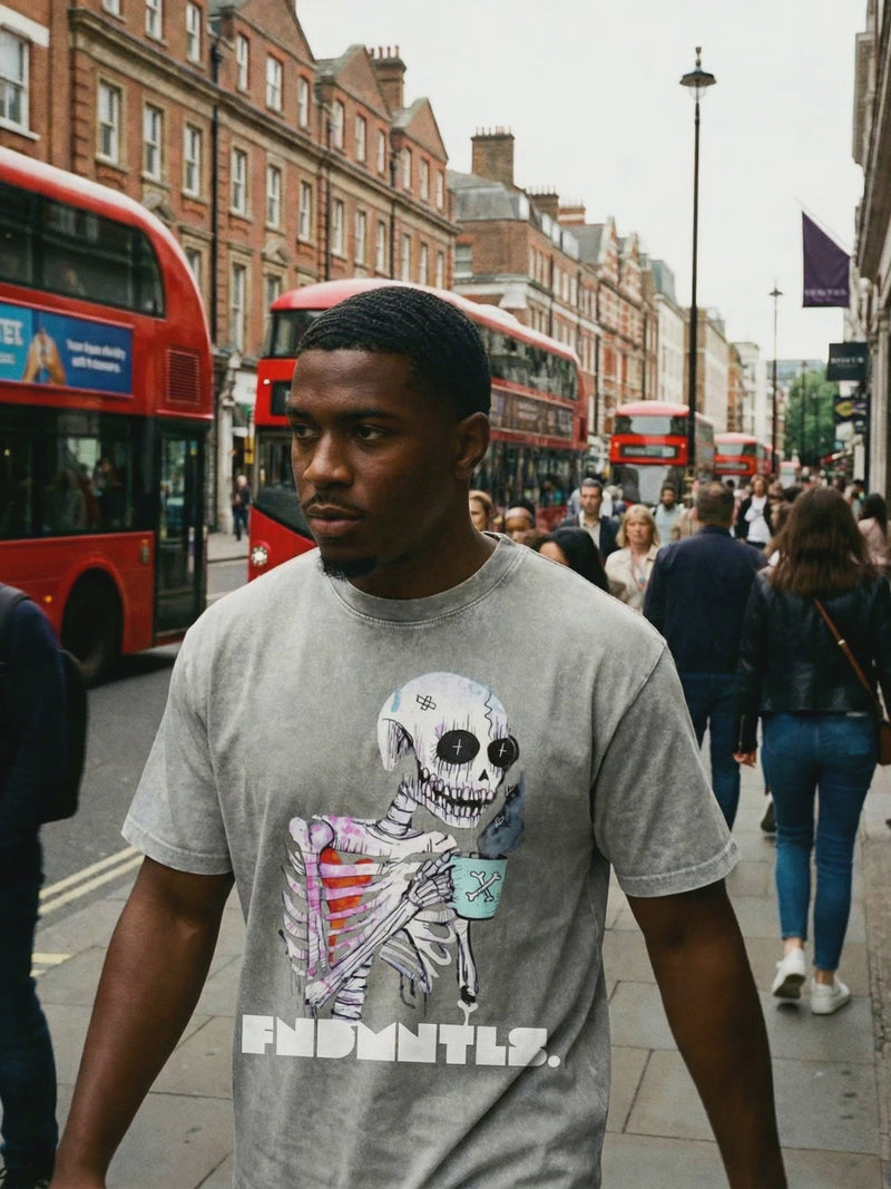 Model wearing Wake UP Oversize Snow Washed T-Shirt in grey with skeleton coffee graphic, walking in urban setting. Stylish cotton tee for men.